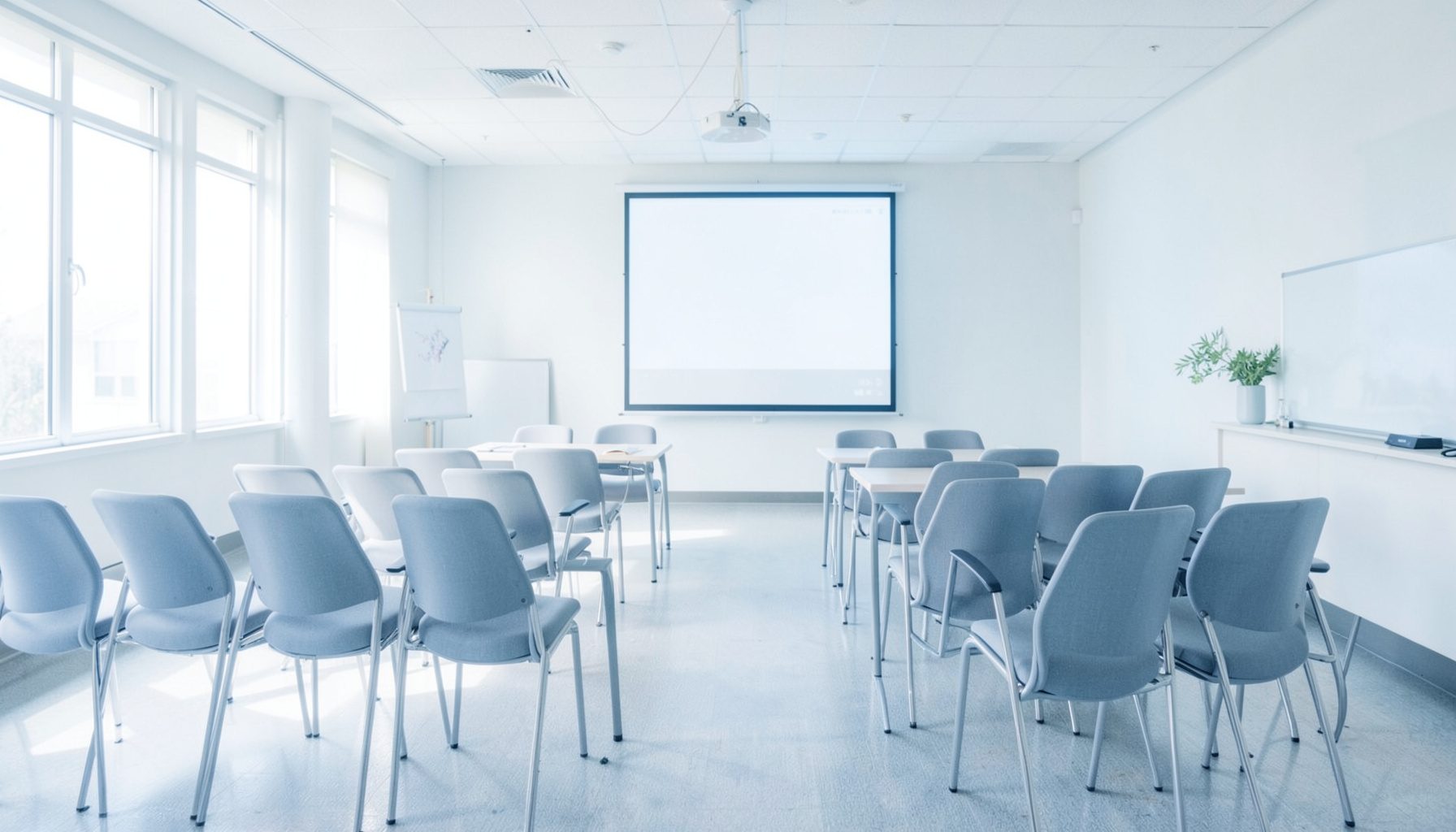 Fotografía aérea y luminosa de una sala de conferencias con sillas dispuestas y una pantalla de proyección, iluminada por luz natural difusa, ambiente académico y acogedor